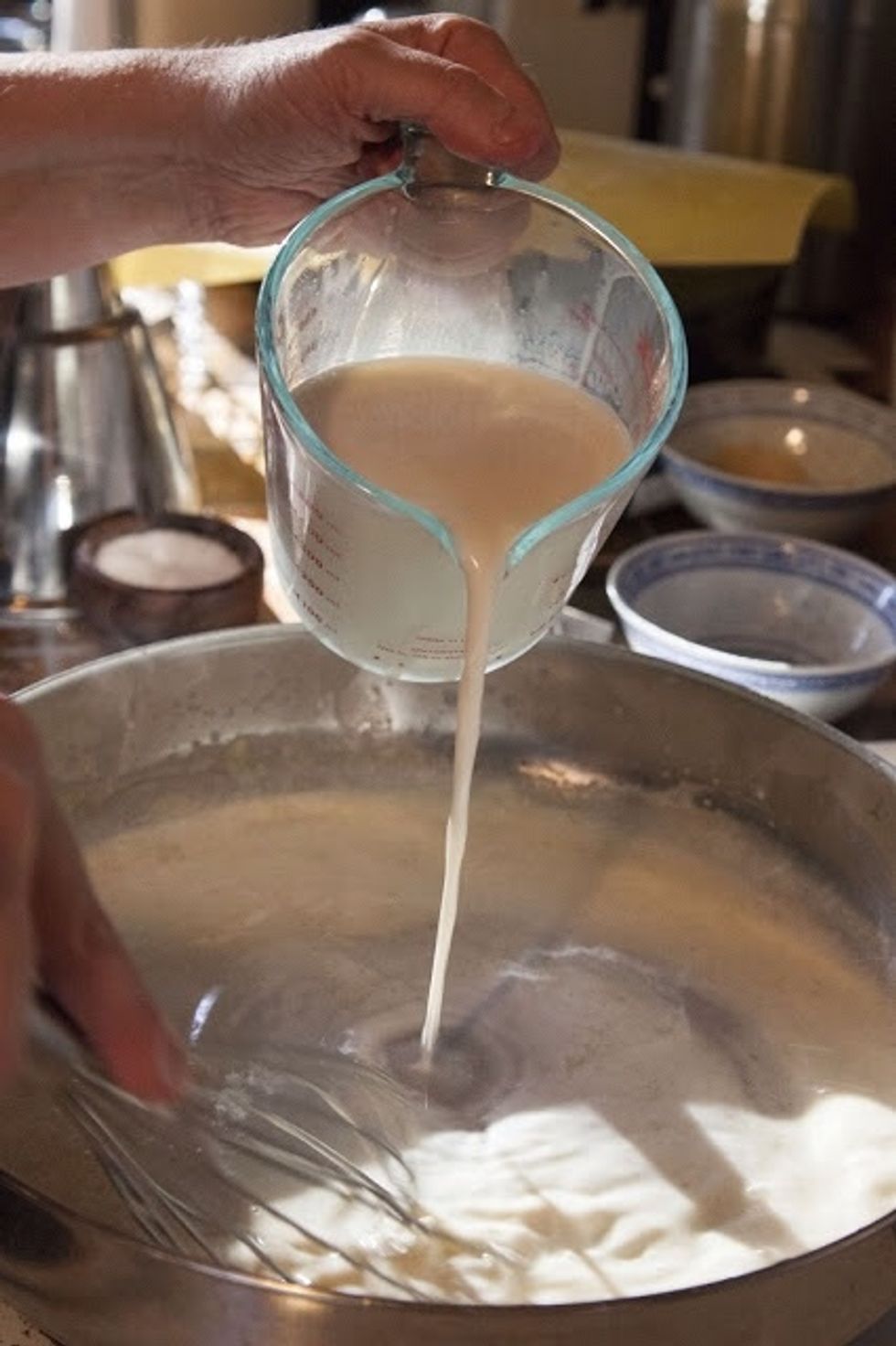 When it's all whisked together, slowly, a bit at a time, add in the heated milk. Keep whisking all the while. Don't stop as you don't want lumpy roux. Whisk the roux until it thickens.