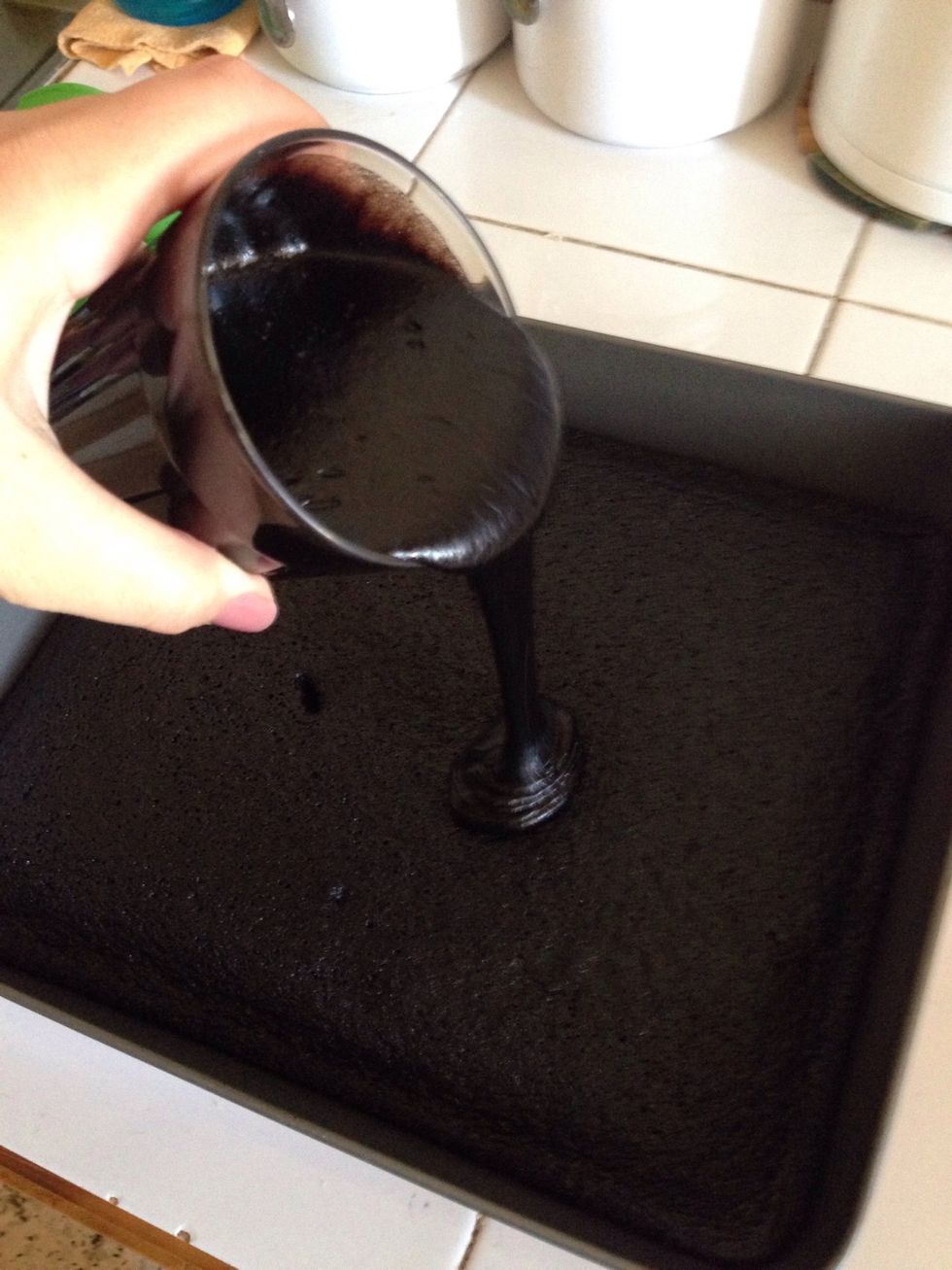 When it's cooked pull it out of the oven since it's hot pour the the cup of the mixture we left before and spread it well using a spatula