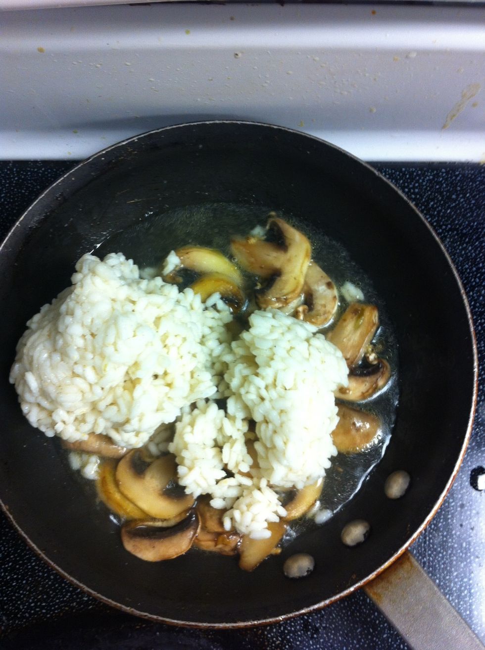 When mushrooms are translucent, add Arborio Rice and Vegetable Stock to pan. Simmer over medium heat, breaking rice chunks.