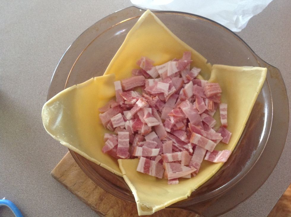 When pastry is done take out the rice and cover the bottom with bacon and cut the excess pastry