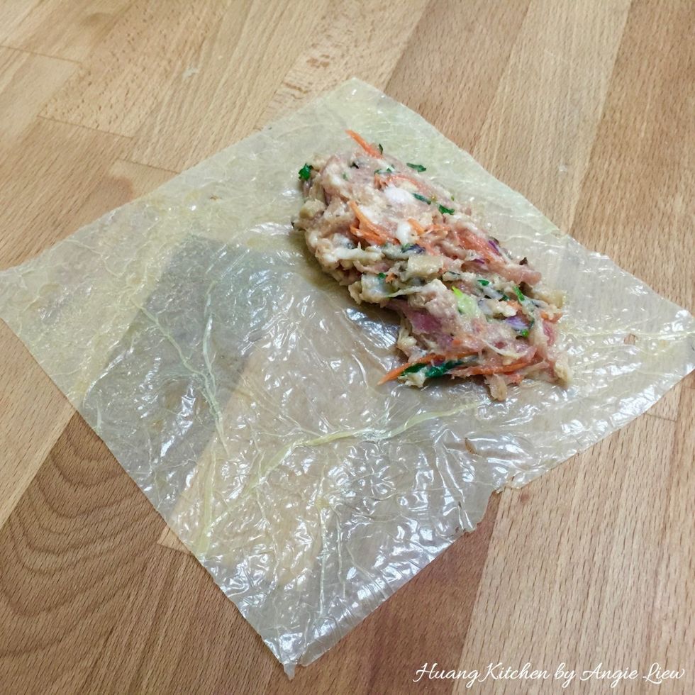 When ready to wrap the meat rolls, spread beancurd skin wrapper flat on a board. Place enough meat filling on the lower half of the beancurd skin, leaving a gap at the bottom and at the sides.