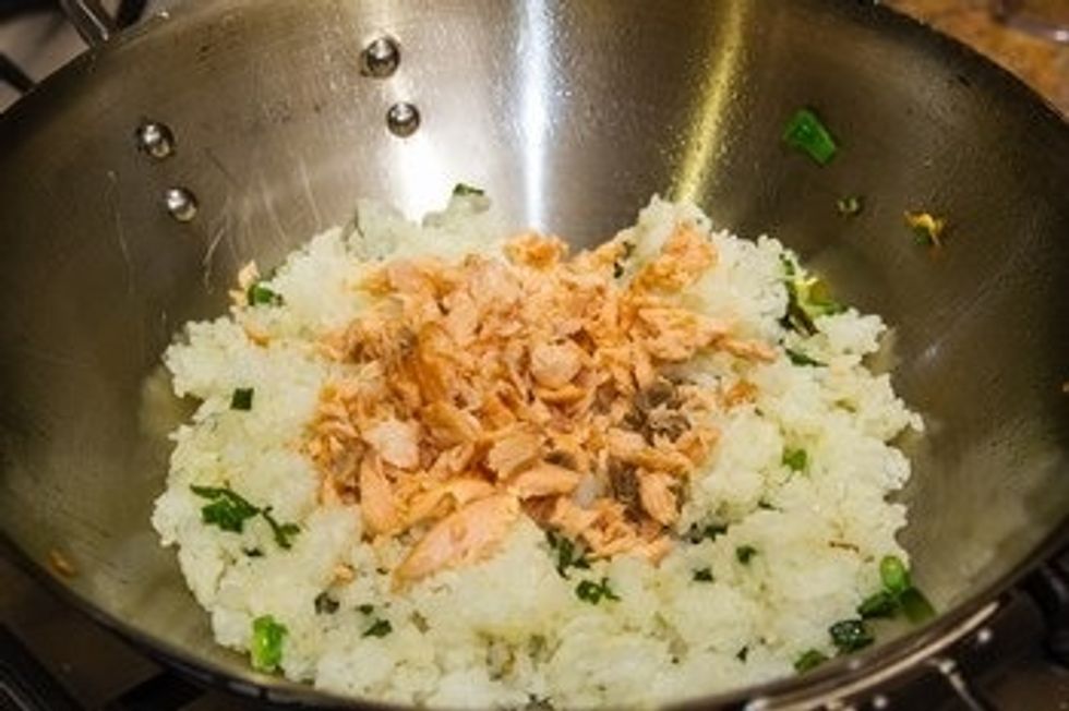 When rice is coated with oil, add the shredded salmon and toss the wok again.