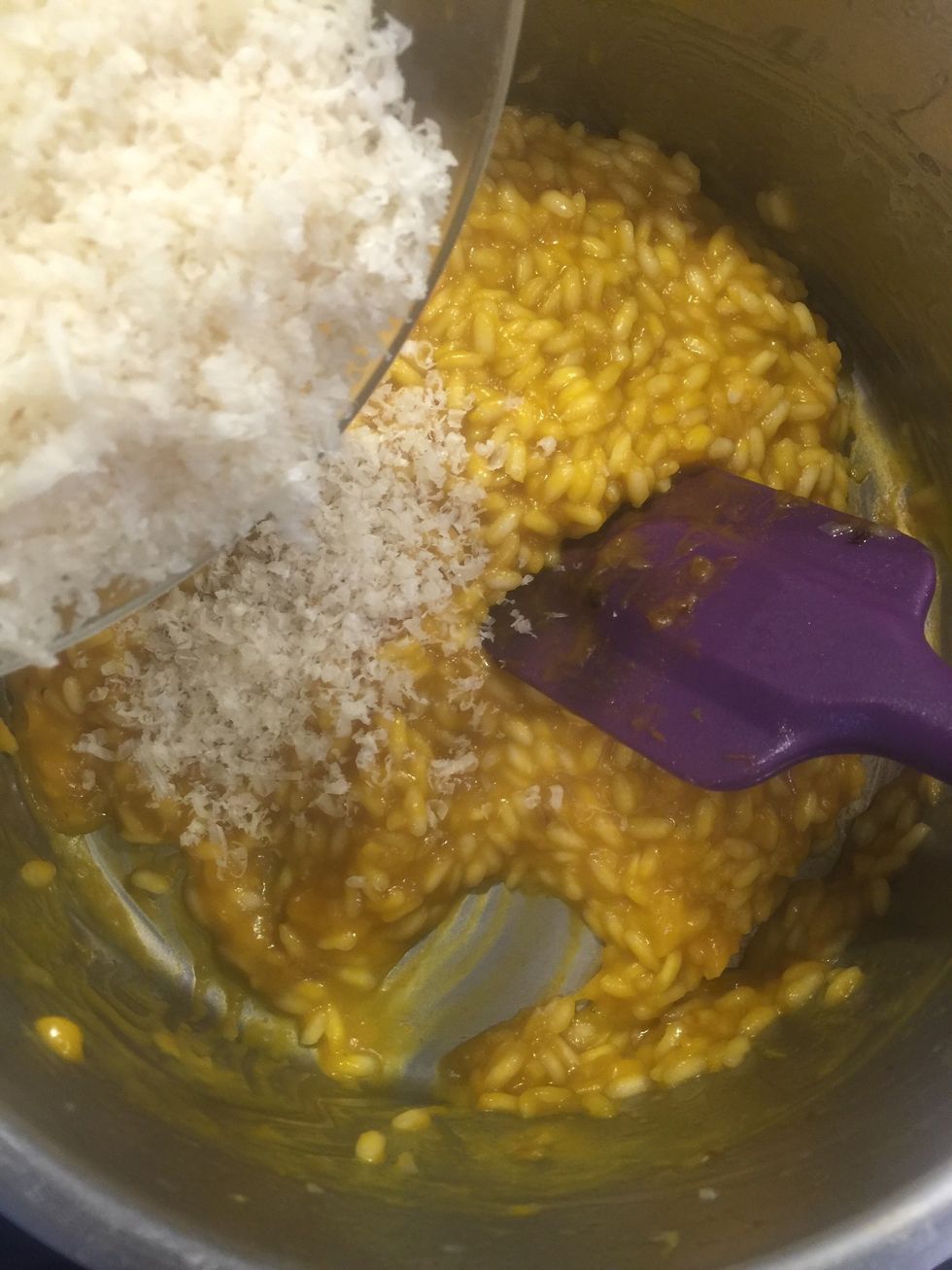 When rice is still al dente and has a very loose consistency, add most of the grated Parmesan cheese