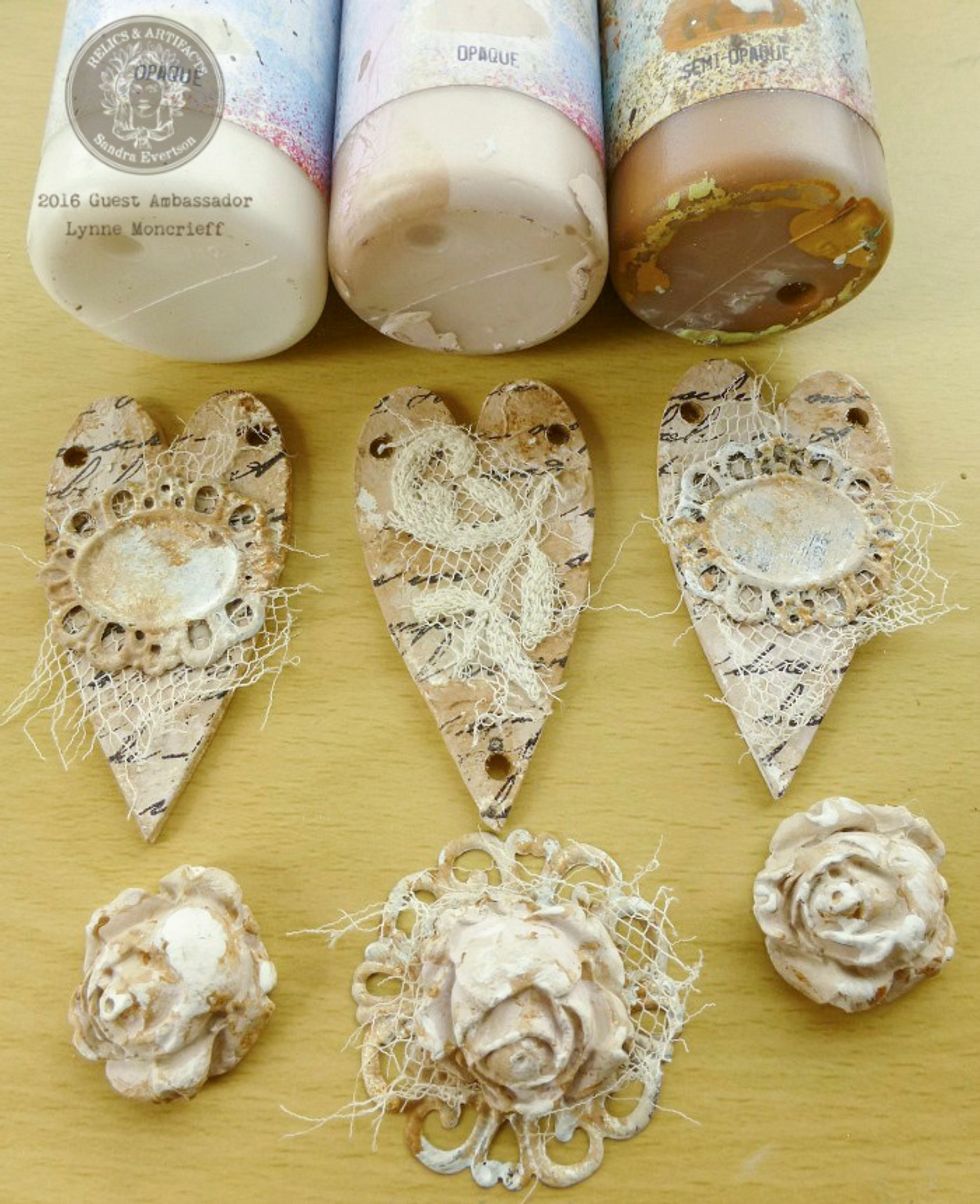 When roses are dry paint with chalk paint. Apply Matte Varnish to all pieces Adhere torn pieces of vintage lace to bezel frames with Gel Medium. Layer rose onto each frame. Adhere each to a heart
