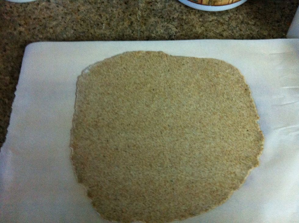 When satisfied with your size, put it over a sheet of parchement paper, it will act as a pizza peel, trust me...use the parchement paper!