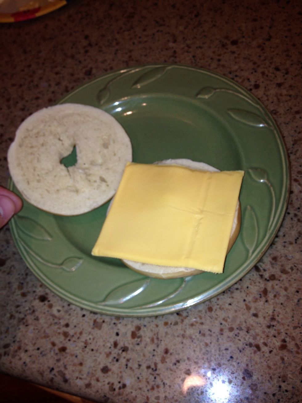 When the bagel pops out of the toaster, lay cheese on it to give it more flavor.