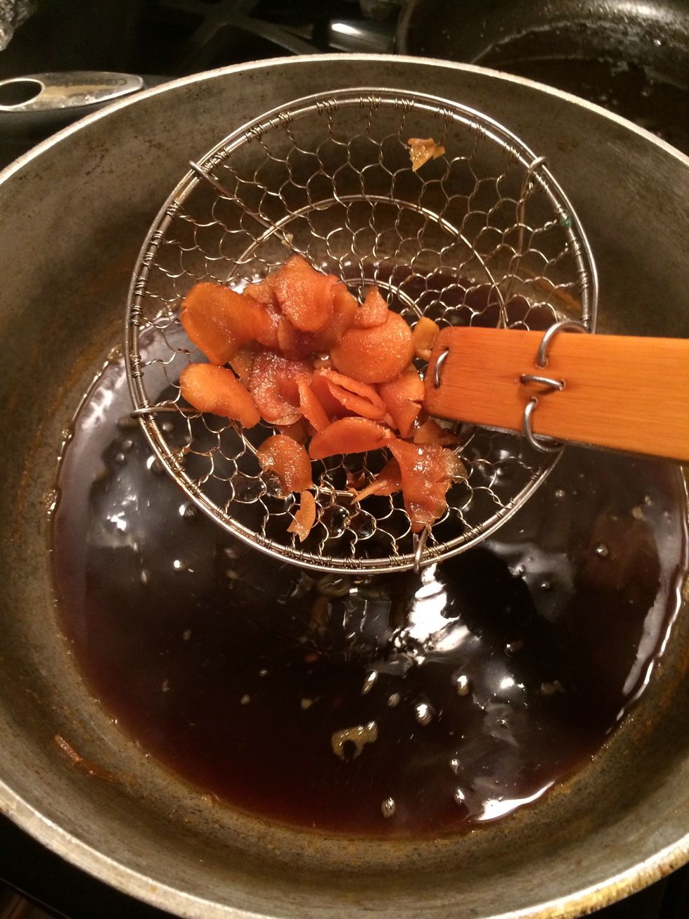 When the broth has simmered and cooked down a bit, we will remove the ginger and garlic.