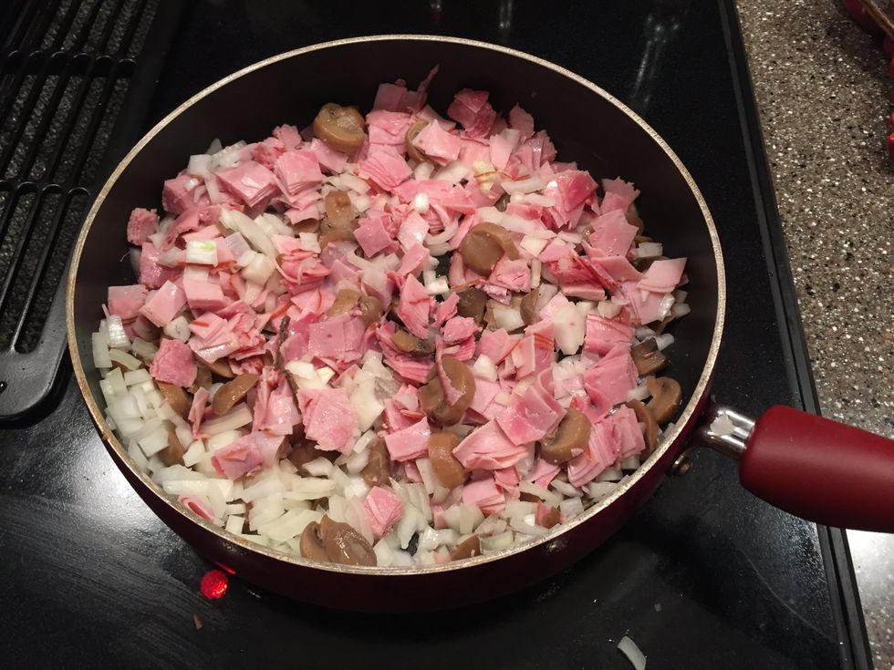 When the butter is completely melted, add the onion, ham, and mushrooms into the skillet and let it cook for approximately 5 minutes still on medium-high heat.