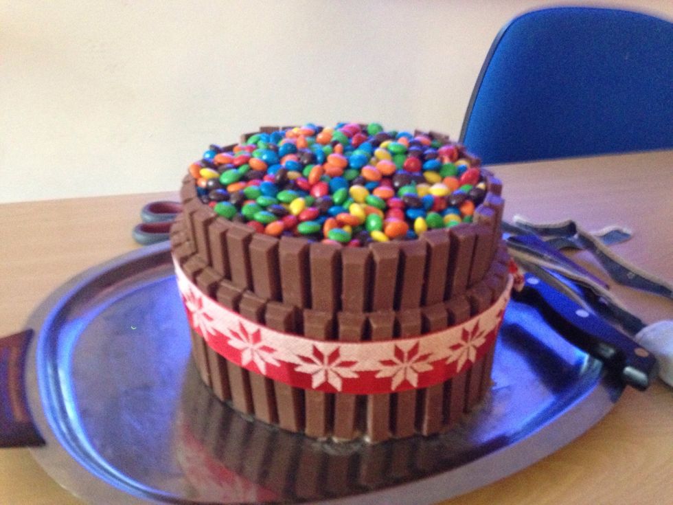 When the cake is cooled, decorate it with kit kat chocolates and m&m's.