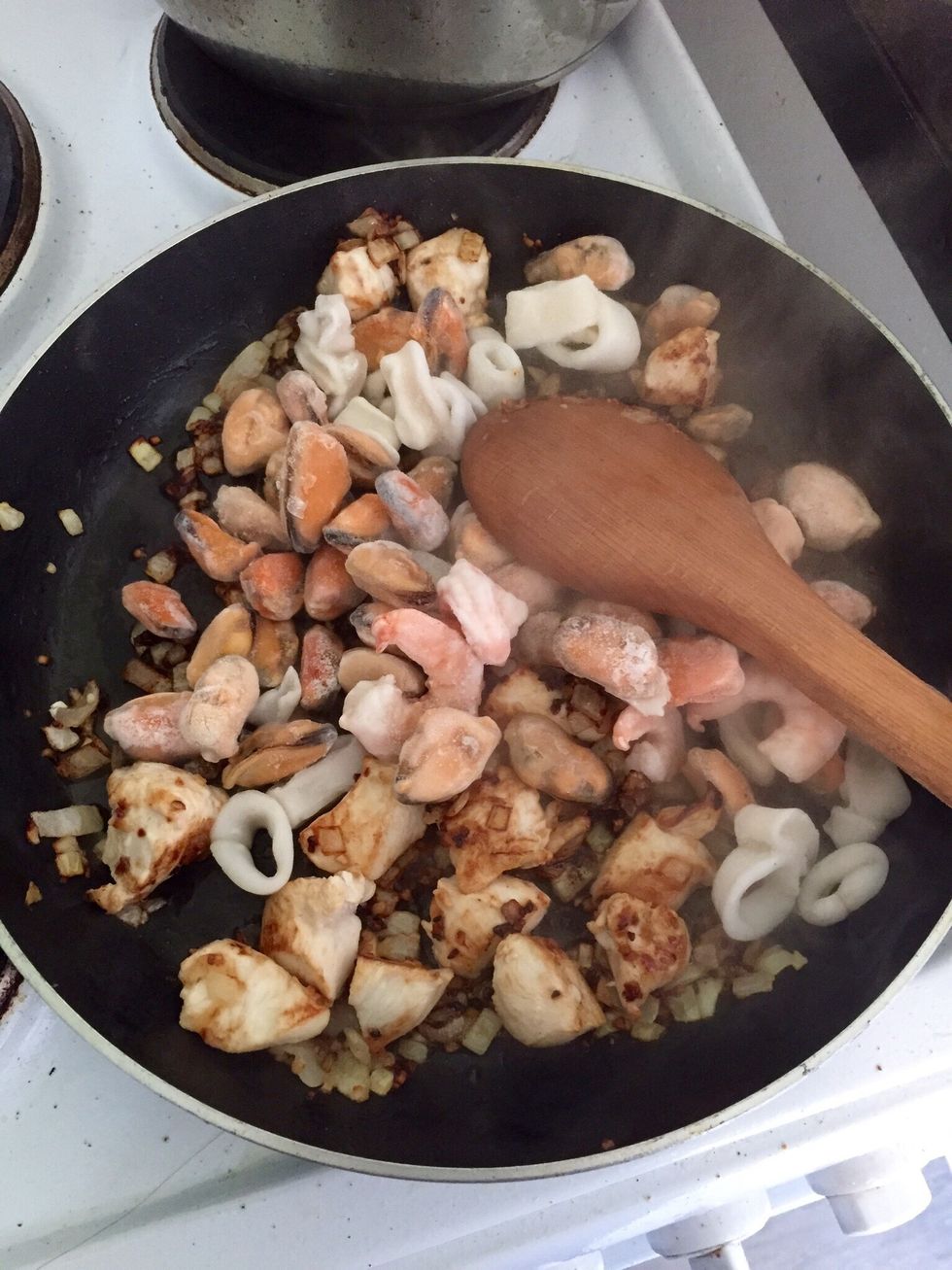 When the chicken is done, add the seafood until it's unfrozen. Usually this type of seafood comes already cooked in the bag. If not, unfreeze and cook