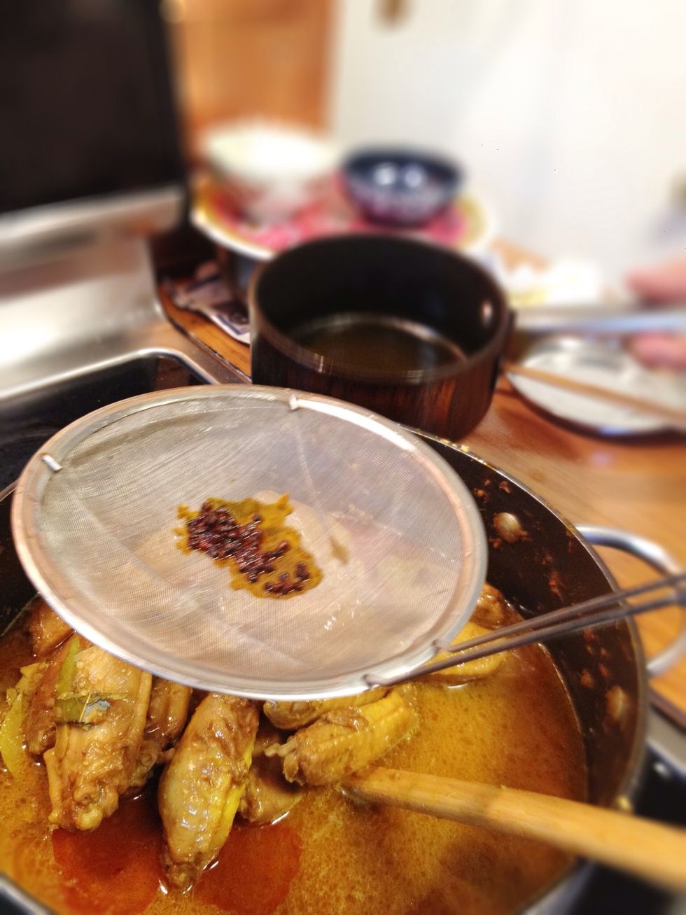 When the curry is simmering, strain the oil and annatto seed into the pot. Turn off the fire.