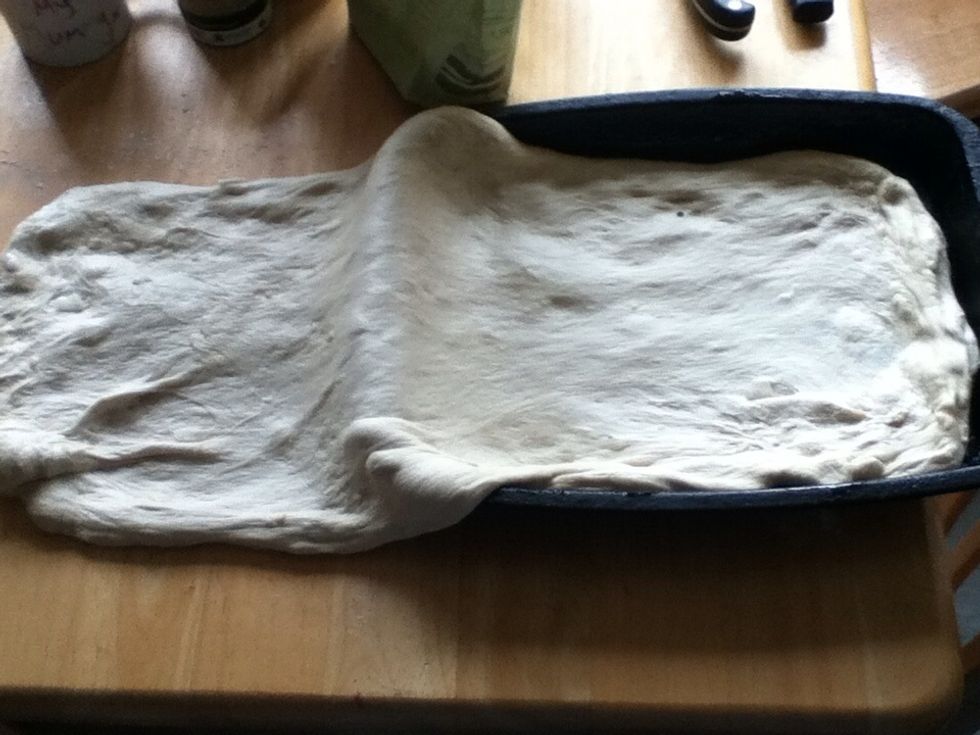 When the dough has risen, turn out onto a floured surface. Stretch it out unroll it is double the length of the tin it's going in. Fill with sweated onion, mushroom, garlic and mozzarella chopped.