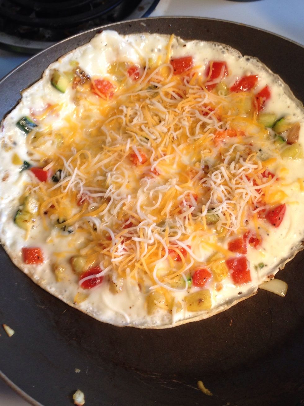 When the eggs start to harden and are able to move around freely, add the cheese over the top.