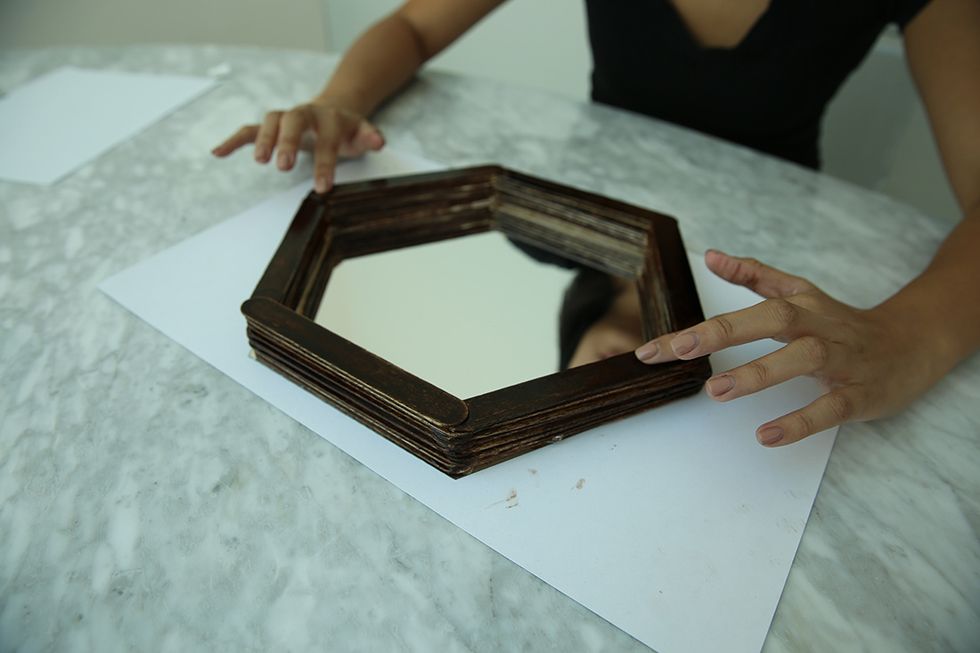 When the frame is dry, flip it over and apply glue to the bottom layer. Then press firmly to the outside edges of your mirror, making sure the edges of the mirror are covered by the frame.