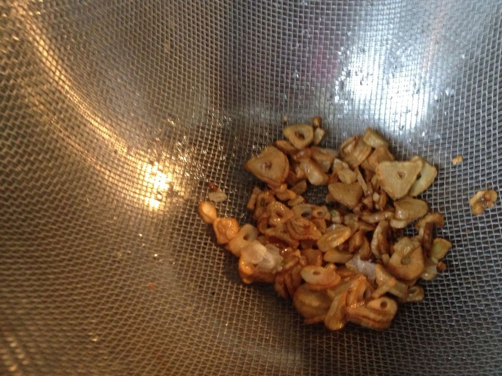 When the garlic turns golden, remove from oil and place in a strainer or colander to drain the oil.