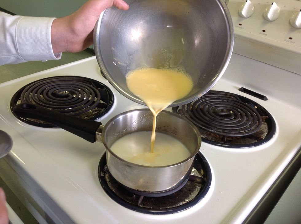 When the milk bubbles on the side, pour a bit of the custard into the milk and stir. Gradually pour the rest of the custard in and keep stirring.
