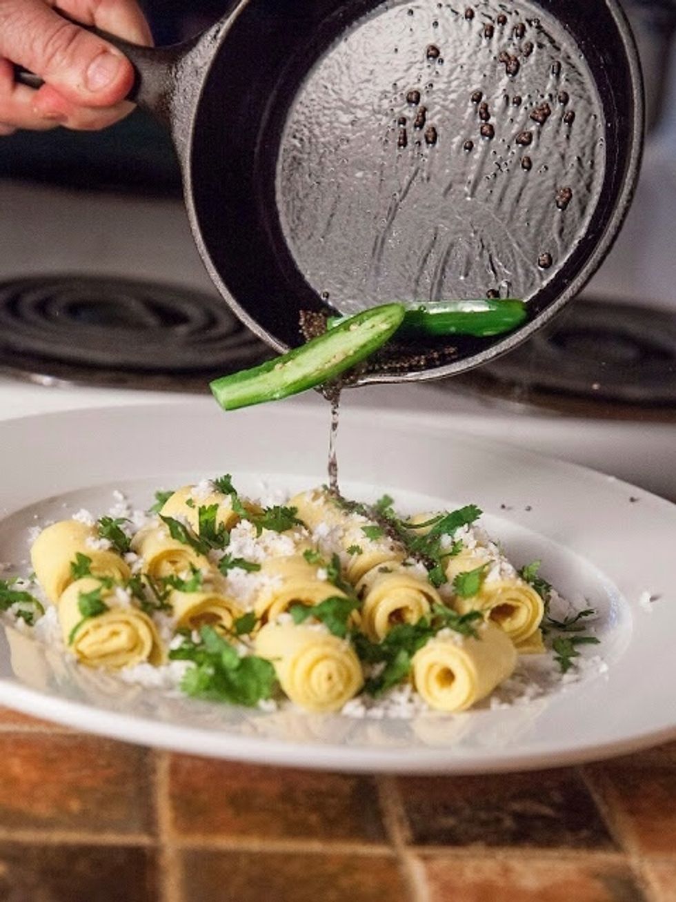 When the mustard seeds start to pop, pour everything over the khandvi on the platter.