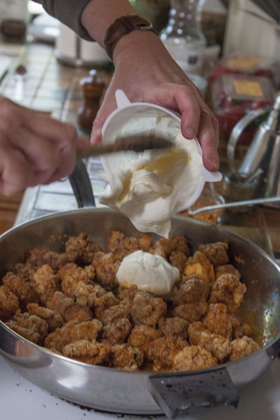 When the oil is hot toss in the chopped ginger, shallot or garlic and stir fry everything for about 30 seconds. Add the fried chicken pieces to the pan, then add the seasoned yogurt to everything.