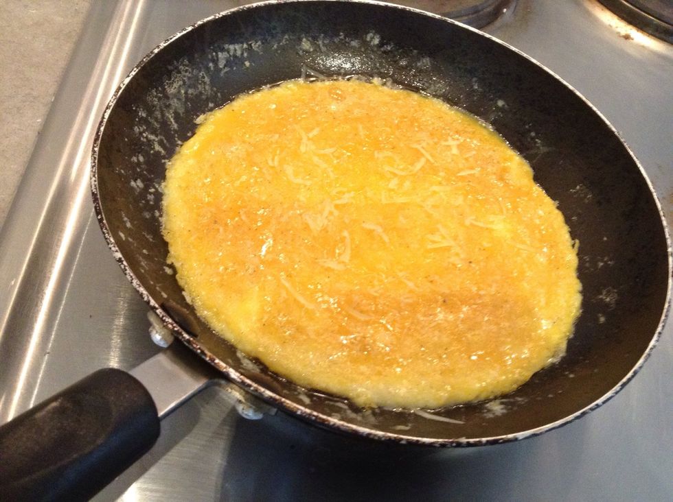 When the omelette begins to cook and firm up, but still has raw egg on top, sprinkle over your Parmesan cheese
