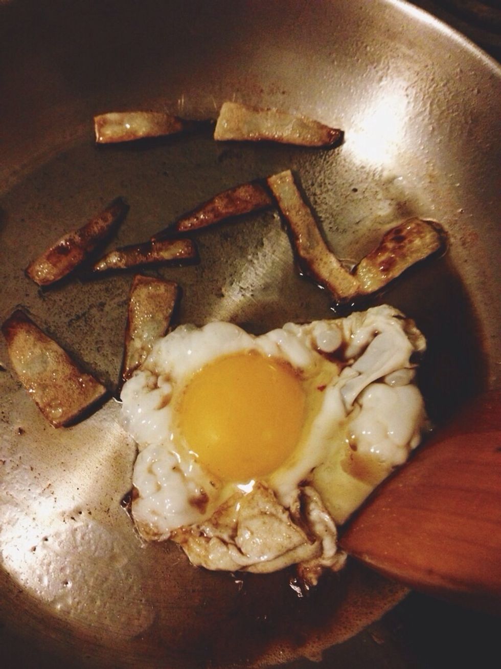 When the onion is nearly done, crack the egg into the same skillet. Push it with a spatula to keep it from spreading out and becoming too big to stay on the muffin.