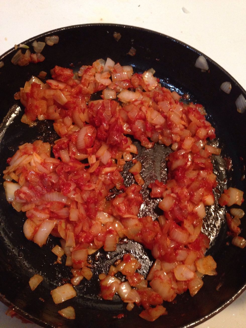 When the onions are soft add the tomato paste. Add more of the reserved chicken juice if it seems a bit dry. Stir for 5 minutes so that the paste is spread out evenly.