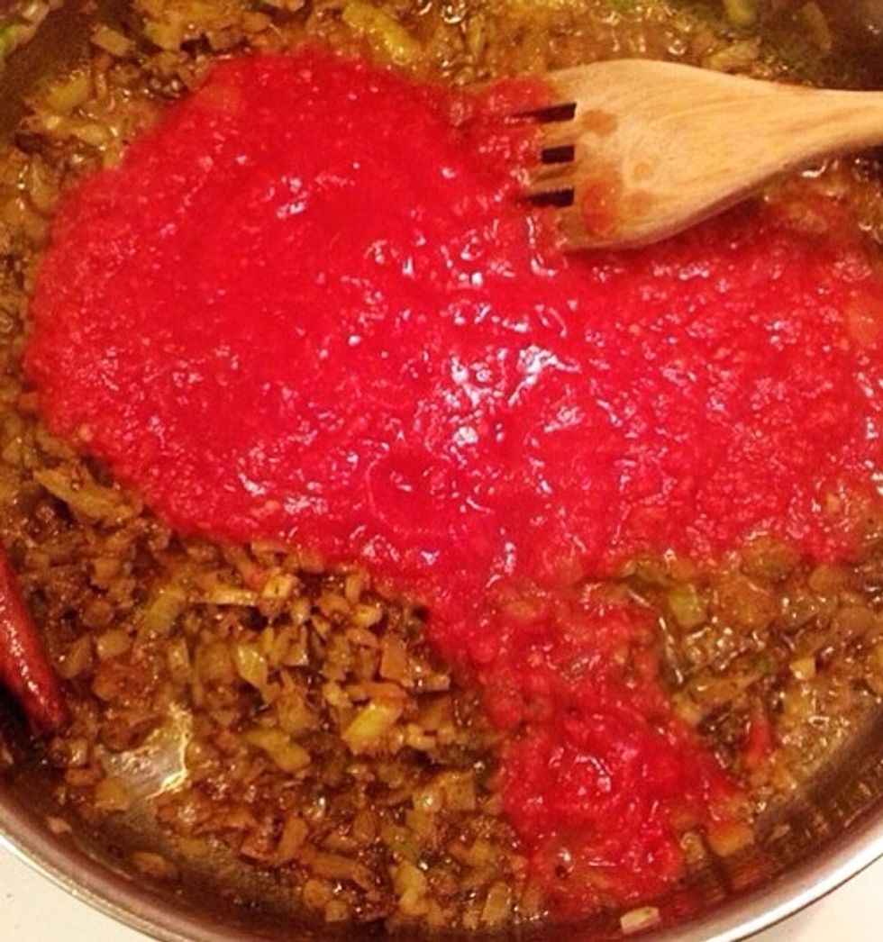 When the spices are well integrated with the onion/garlic/chili mix, add the can of tomatoes.