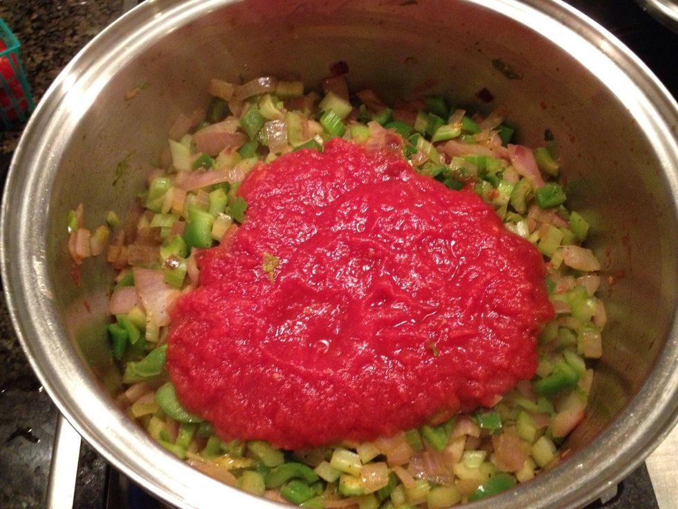 When the vegetables are soft, add in the crushed tomatoes and stir gently.