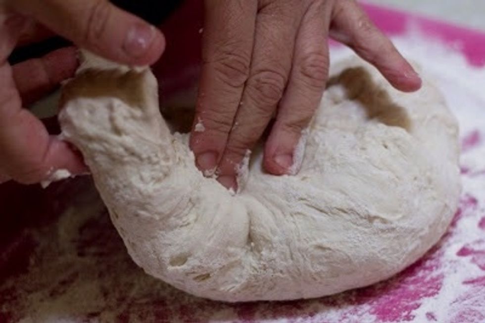 When you are ready to bake the bread, flour a board, moisten your hands to prevent the dough from sticking, and scoop the  dough onto the board.