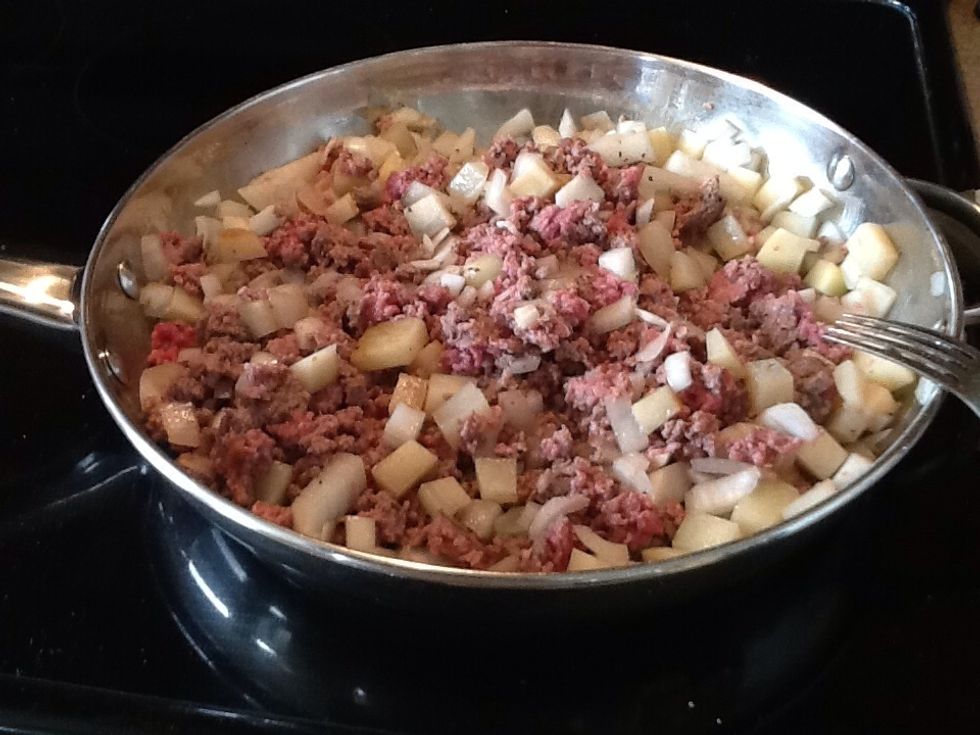 When you get it all mushed together, it will look like this. You can see the onion and potato pieces are already cooking up nicely. Cooking the onion like this will add more flavor to the meat.