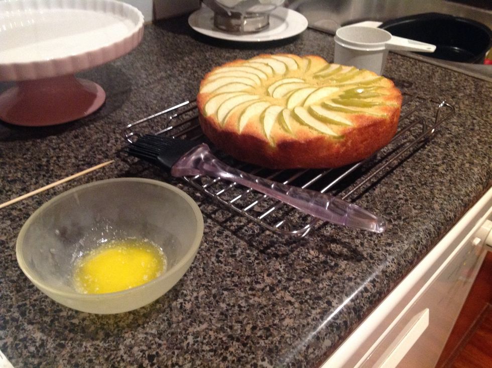 When you have checked your cake with a skewer, and it's ready, take it out and turn it top side up onto a wire rack. Brush hot cake with melted butter.