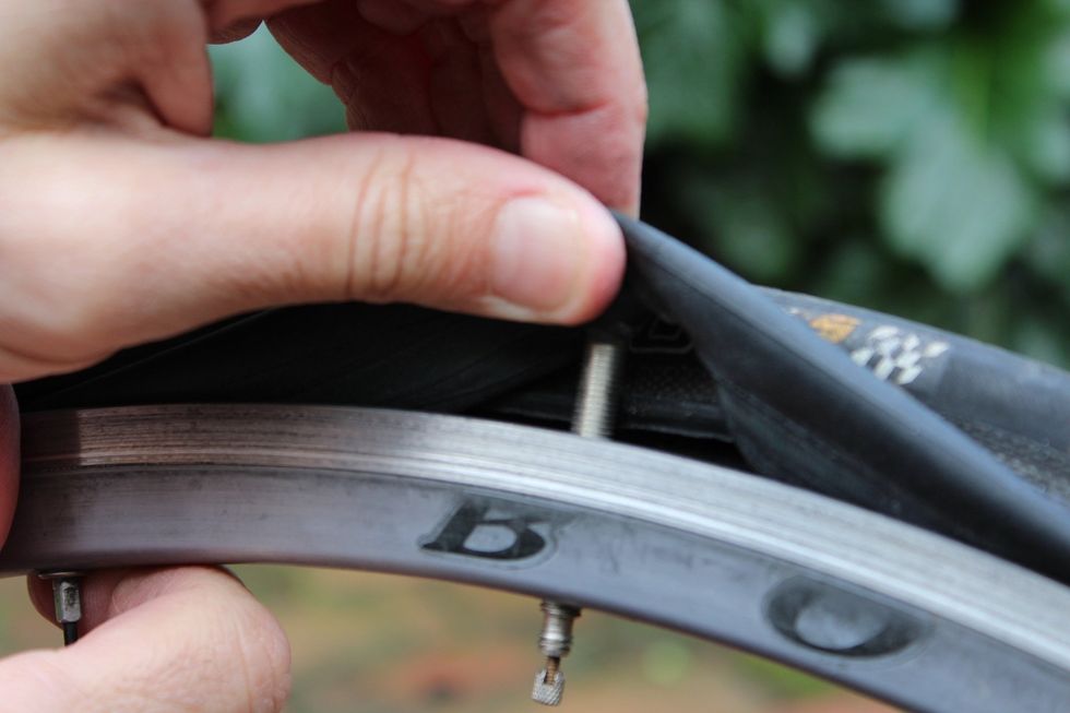 When you have loosened the tire from the rim enough to pull it off, push the valve stem through the hole in the tire, and pull the whole tube out from the tire.