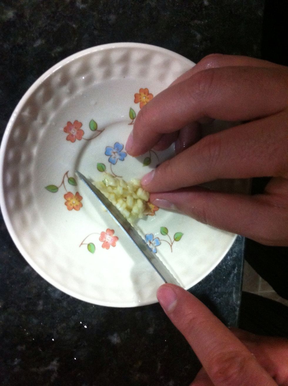 When you're done with all the basil, chop your garlic clove. Add it to the processor and blend until it dissolves into the mixture.