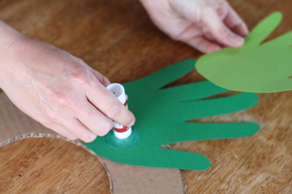 When you've arranged your handprints the way you like them, glue them one at a time onto the cardboard.