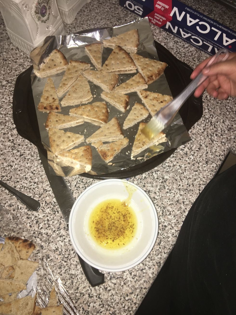 When you've finally added all the pitas take your mixture and brush it on one side of the pita bread slices.