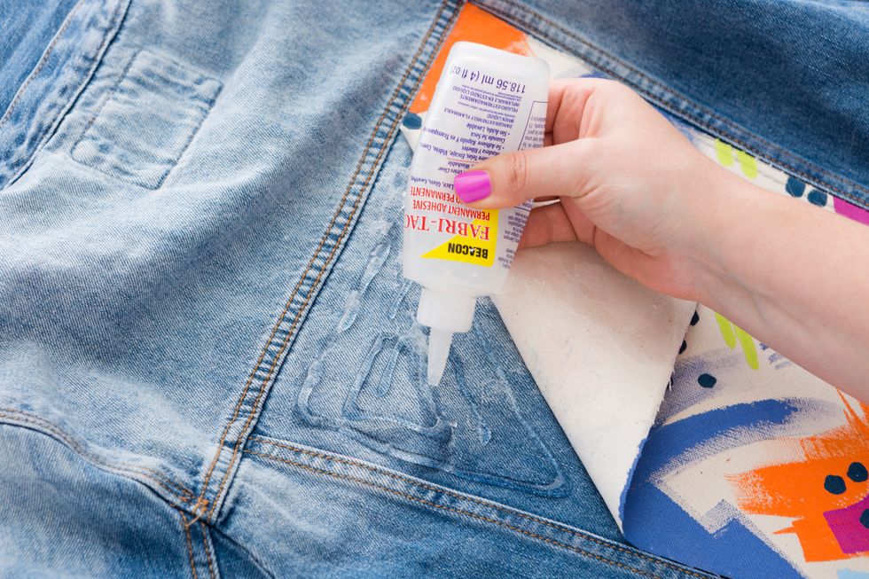 When your canvas panel is completely dry, grab your fabric glue and cover the matching panel on your denim jacket with a spiral of glue.