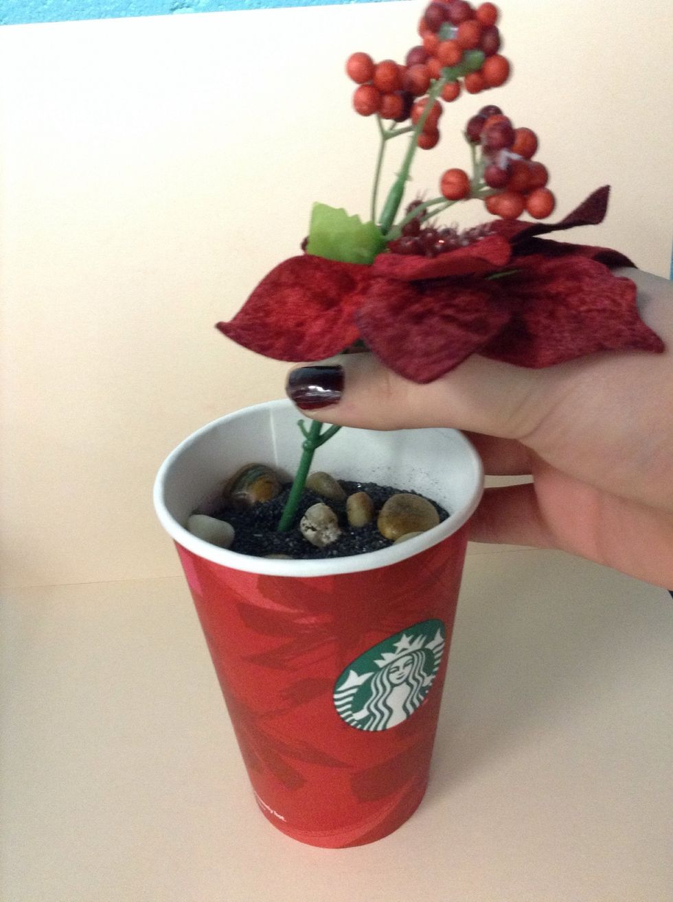 While glue gun is heating, arrange your flowers/plants into the soil or sand. I'm choosing to use red silk flowers because they require no maintenance and look good for the holiday season!