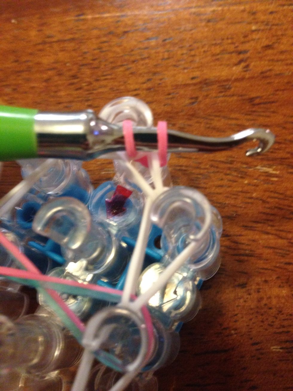 While holding one side of the band, take your hook and basically take it out of the bands, taking the single band with it. It will make the single band wrapped around the others so they won't fall off