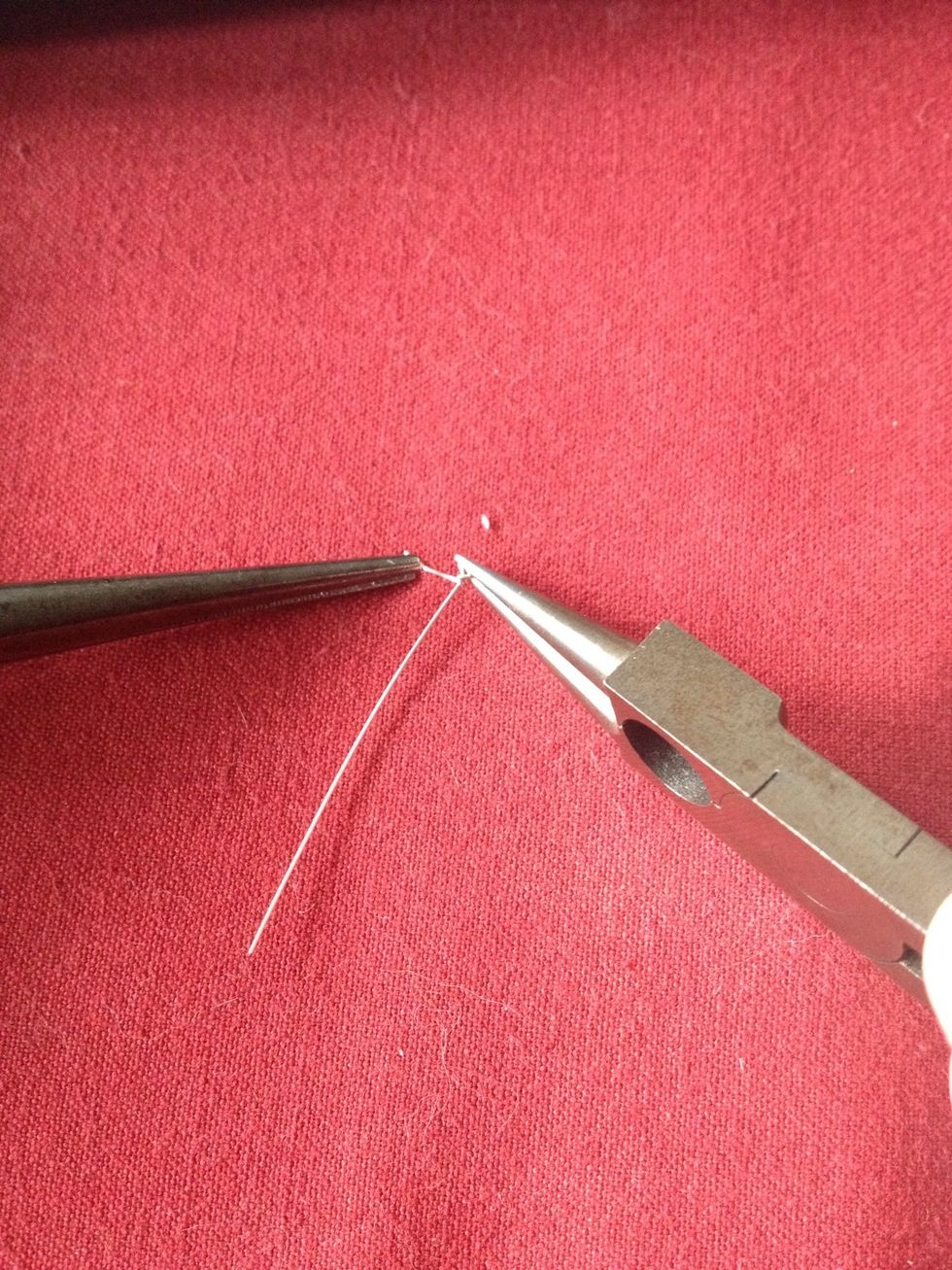 While holding the loop with one pair of pliers, wrap the short end of the wire around the base of the loop several times with the other pair, the snip off the excess wire with a wire cutter.