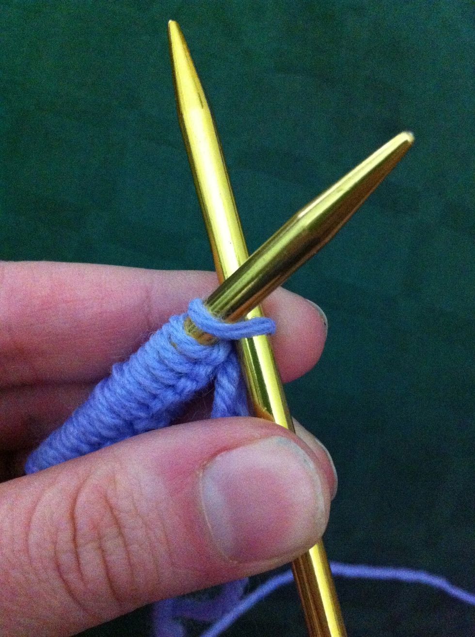 While holding the needle with cast-on stitches in your left hand insert the other needle into the first stitch from front to back.