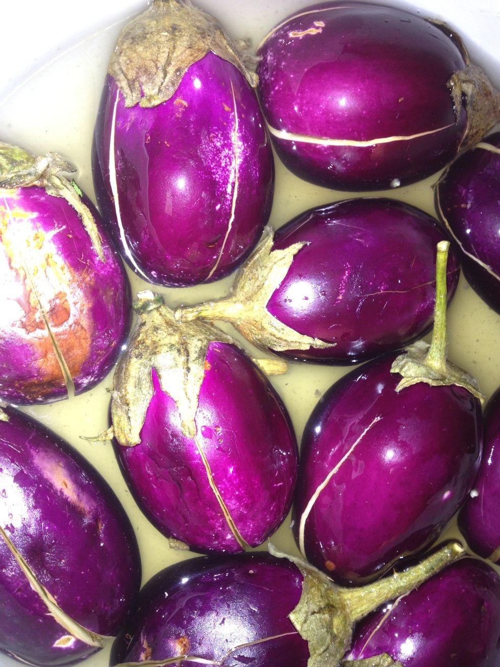 While its boiling slit the eggplant into four slices and keep the stems on and put them in salt water for a minute if they have a bitter taste it gets washed coz of salt