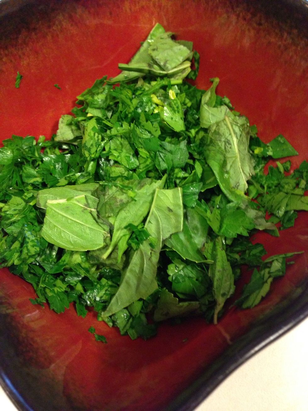 While sauce cooks, chop fresh herbs and split the basil into two piles, about equal amounts the parsley about a 2-1 ratio