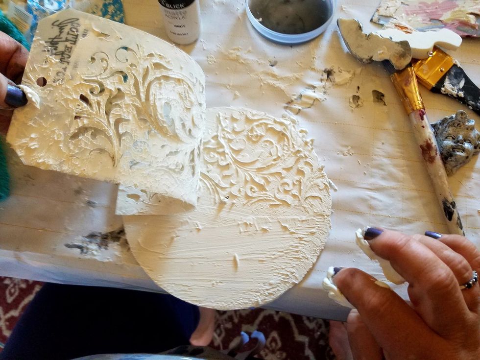 While still wet lay down filigree stencil pressing slightly and pull back up to make imprint replace around circle. Allow to dry As you do the exact same to the larger disc..minus the Cd Measure.