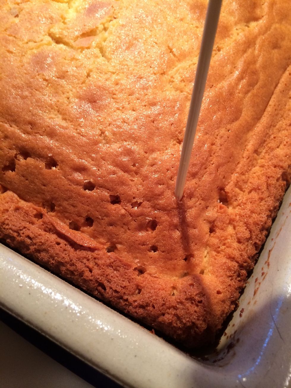 While the cake is still warm, use a skewer and poke holes over the entire surface of the cake.