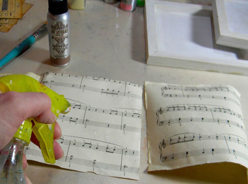 While the canvases are drying, let's age the music paper. Cut 3 sheets to fit the inside of the canvases.  Spritz with water.