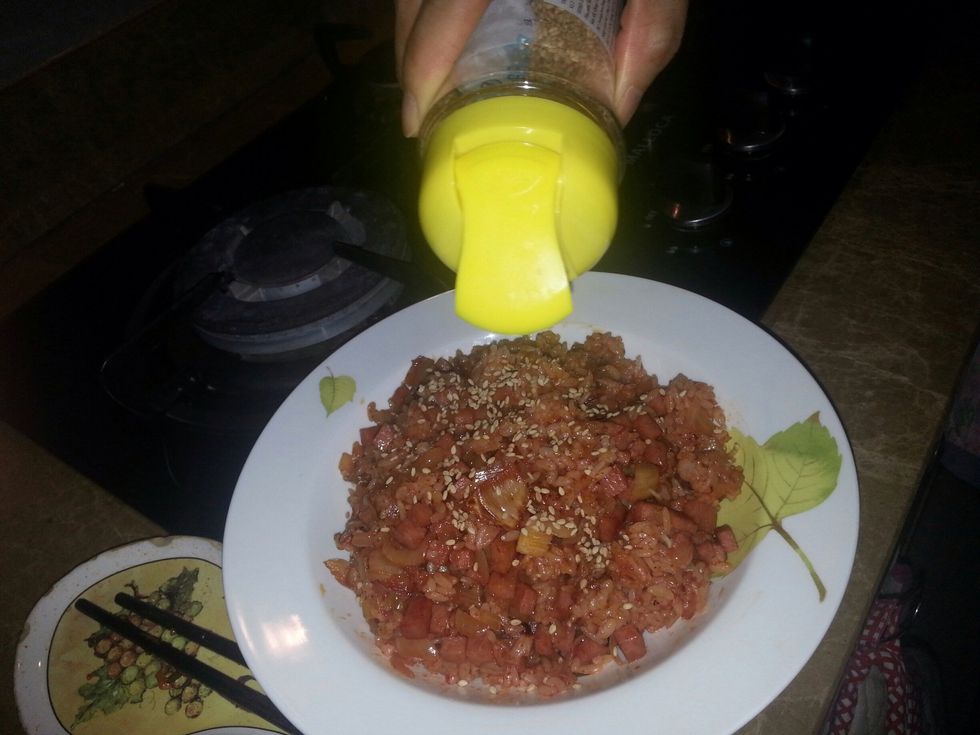 While the egg is getting fried on the other side, pour sesame seed around the rice.