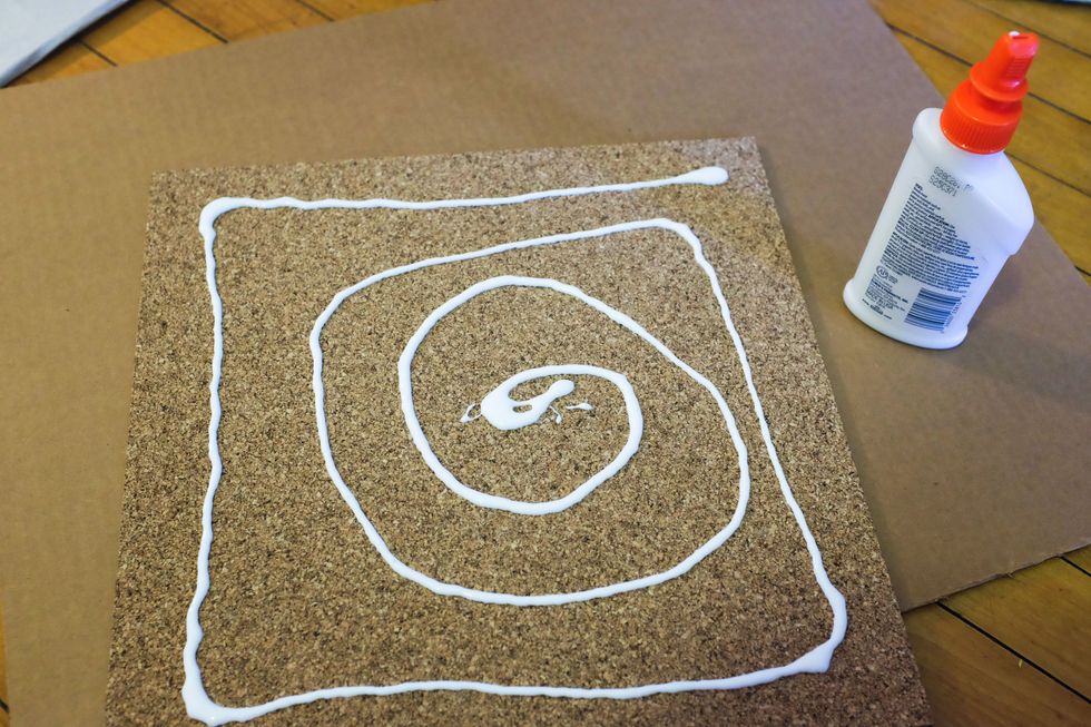 While the first coat on your frame dries, glue your cork tiles to the frame's backing. You can trace the backing first and cut the tiles with scissors to get the right size.