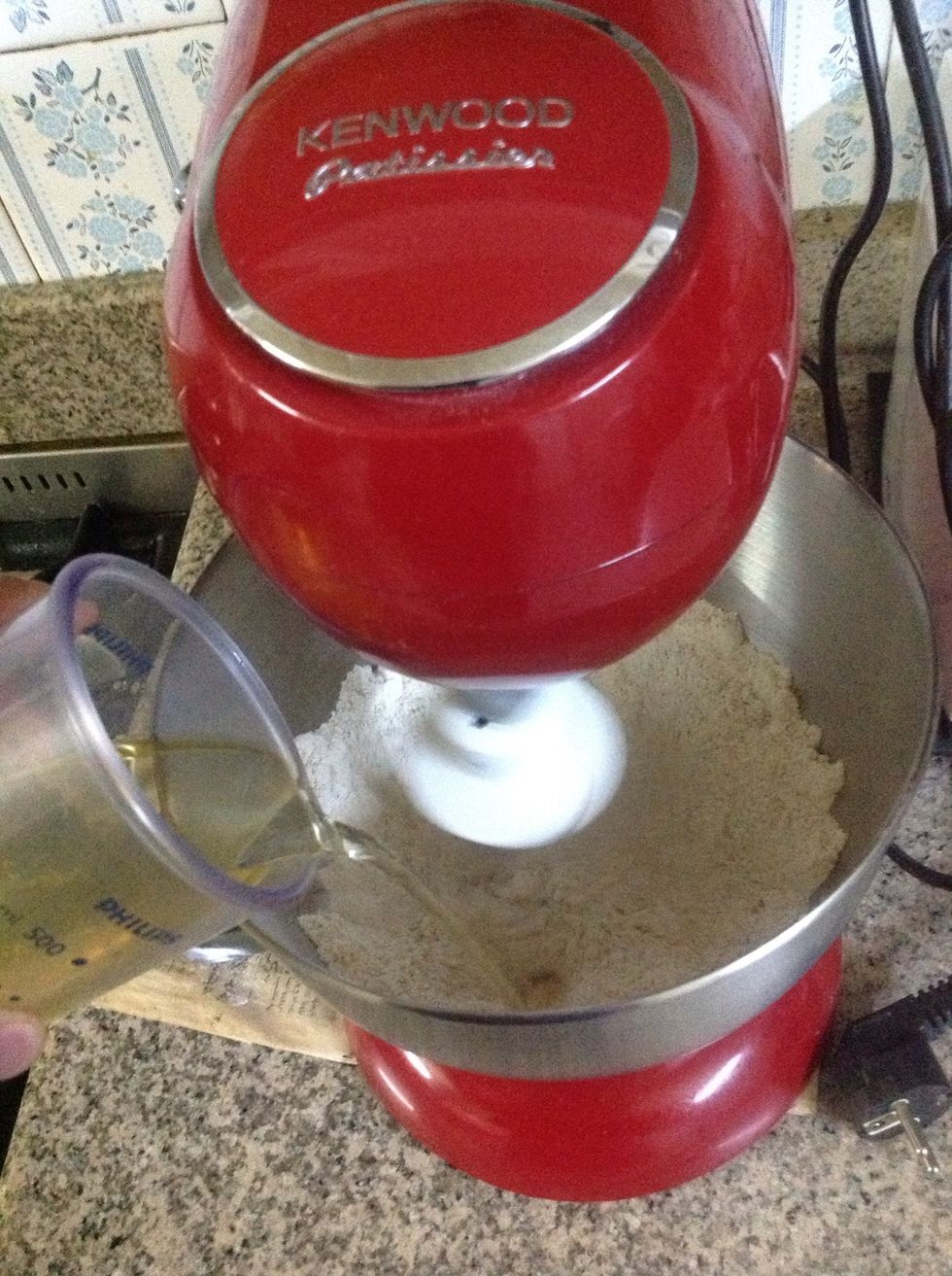 While the mixer is running on slow, add the wet ingredients. Mix on slow untill it begins to come together, then increase speed to medium. If you are mixing by hand, you can start kneeding it now.