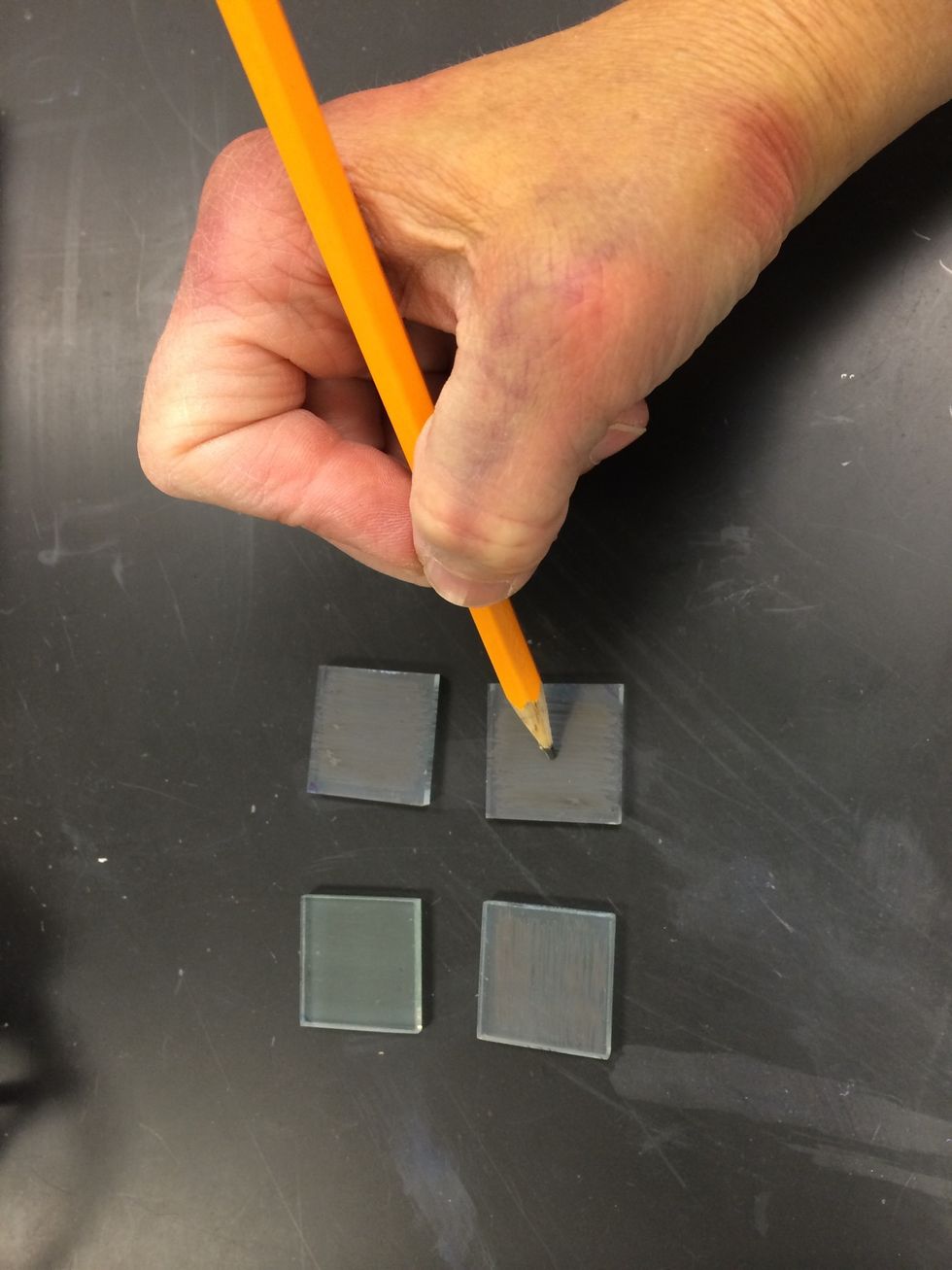 While the TiO2 electrode is being stained, make the counter electrode from the other piece of glass. Using a soft pencil or graphite rod, apply a light carbon film to the entire conductive side.