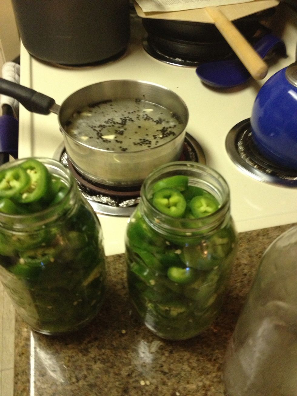 While vinegar mixture is simmering, stuff jalepenos  into quart sized jars. A pound fills 1 jar to the rim.