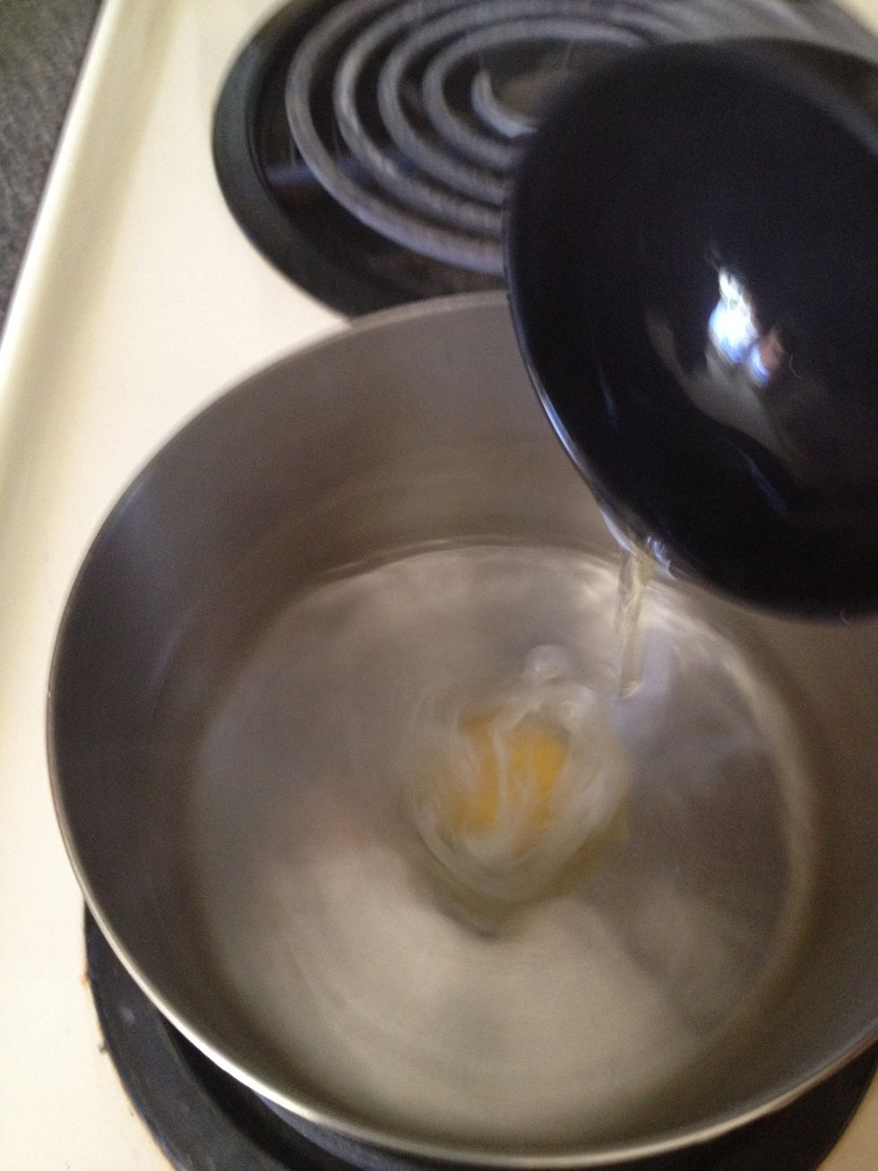 While water is still swirling, quickly but gently drop egg into the center of the whirlpool.